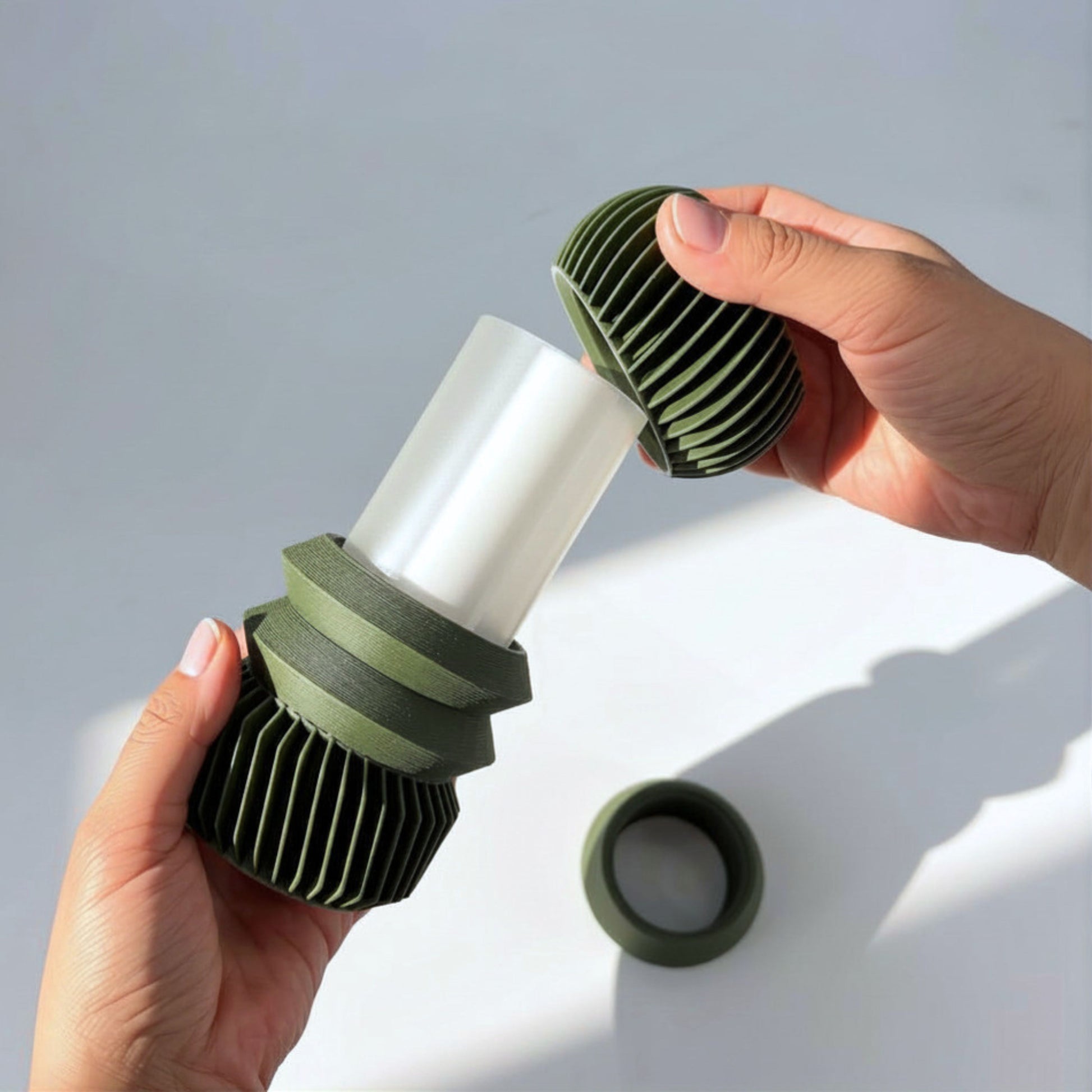 Hands assembling tiered components onto the Matcha Green MODU Vessel, modern modular 3D printed decor by Sonnihaus