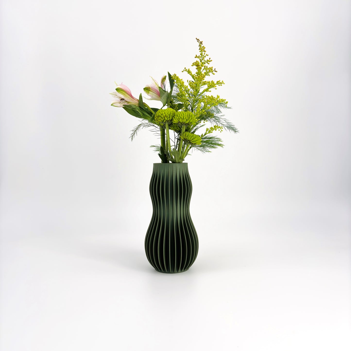 A collection of five 3D-printed HOLI vases in various colors including white, beige, brown, green, and black, displayed in a row with a white flower in the background.