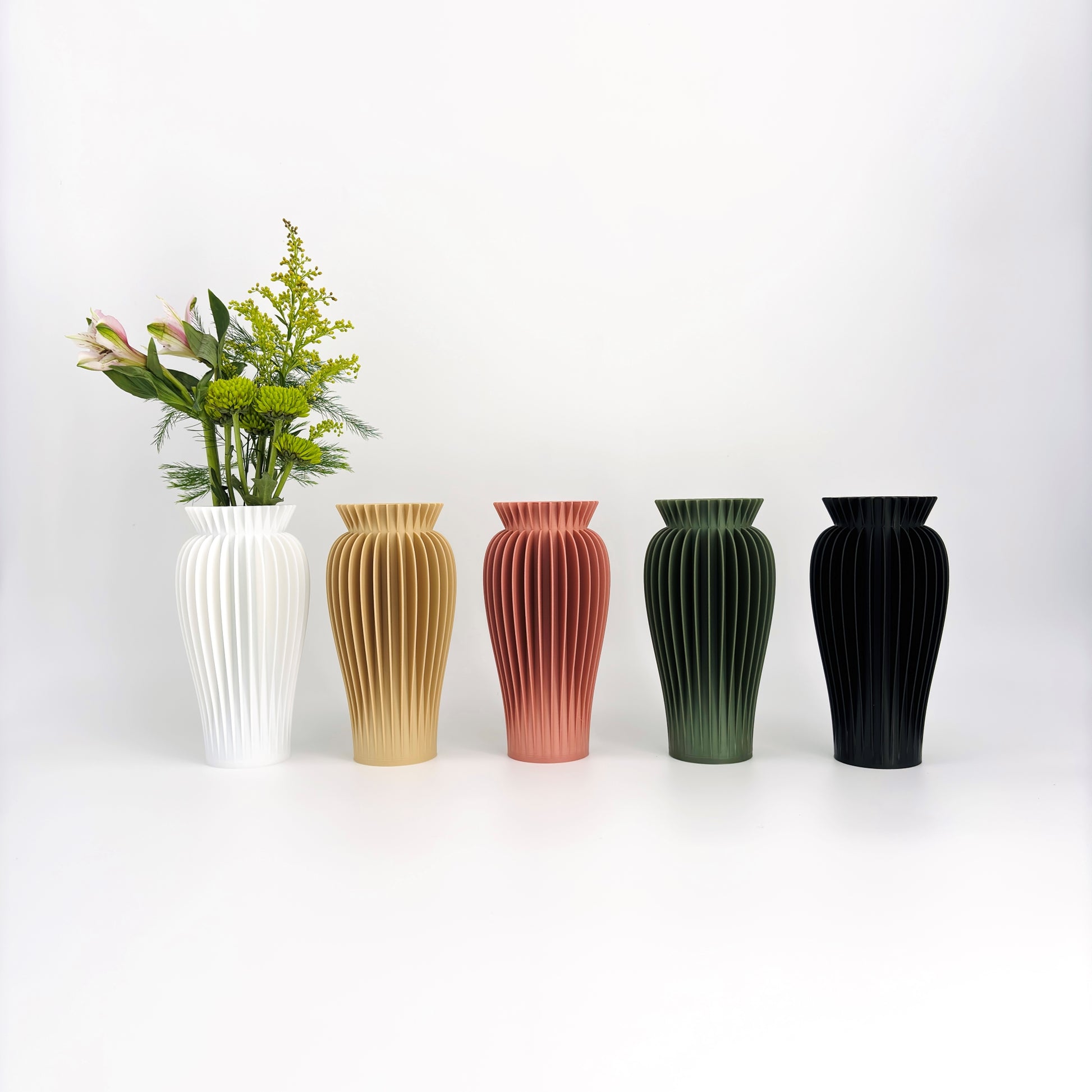 A selection of four MAE vases in a row, featuring a 3D printed design with ribbed textures. The vases are displayed in white, beige, green, and black colors.