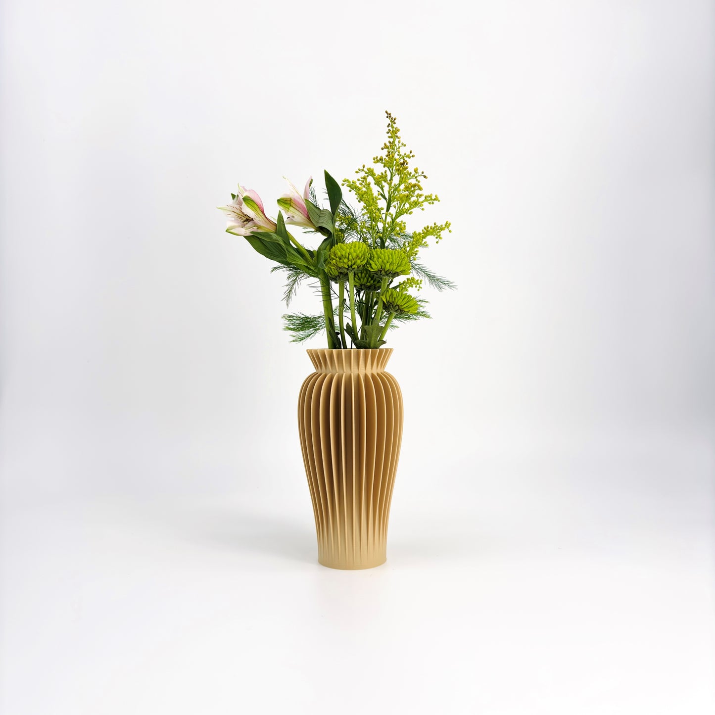 A collection of five MAE Vases in various colors including white, pink, beige, green, and black, displayed against a white background with a floral arrangement in the background.